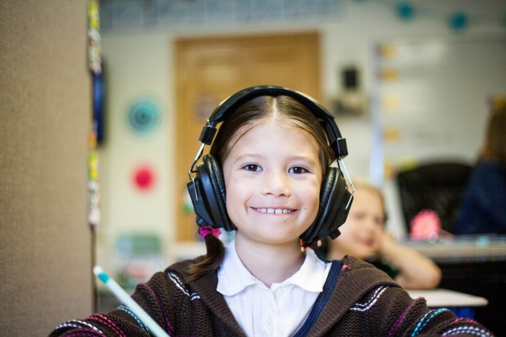 Female student smiling, wearing headphones in classroom
